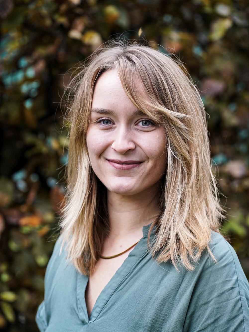 Frau mit blondem Haar und blauem Oberteil.