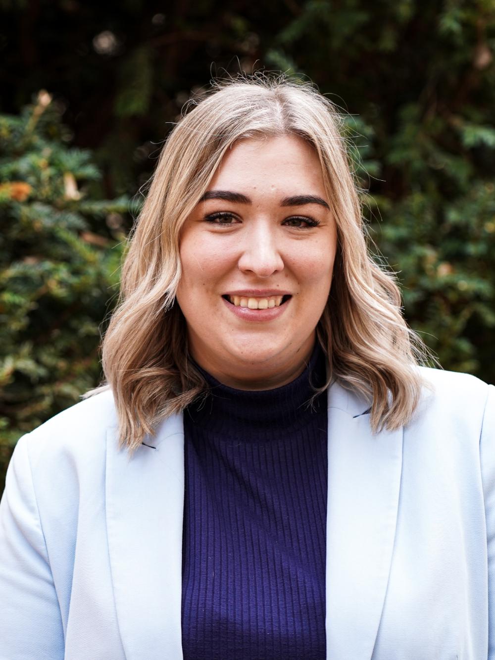 Frau mit blondem Haar und hellem Blazer.