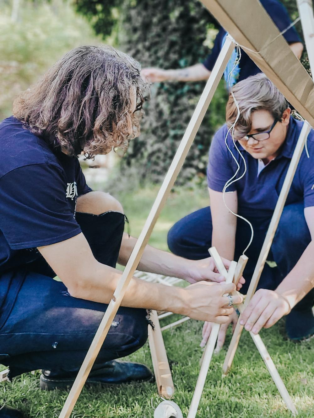 Zwei junge Männer, welche eine Konstruktion aus Holz bauen.